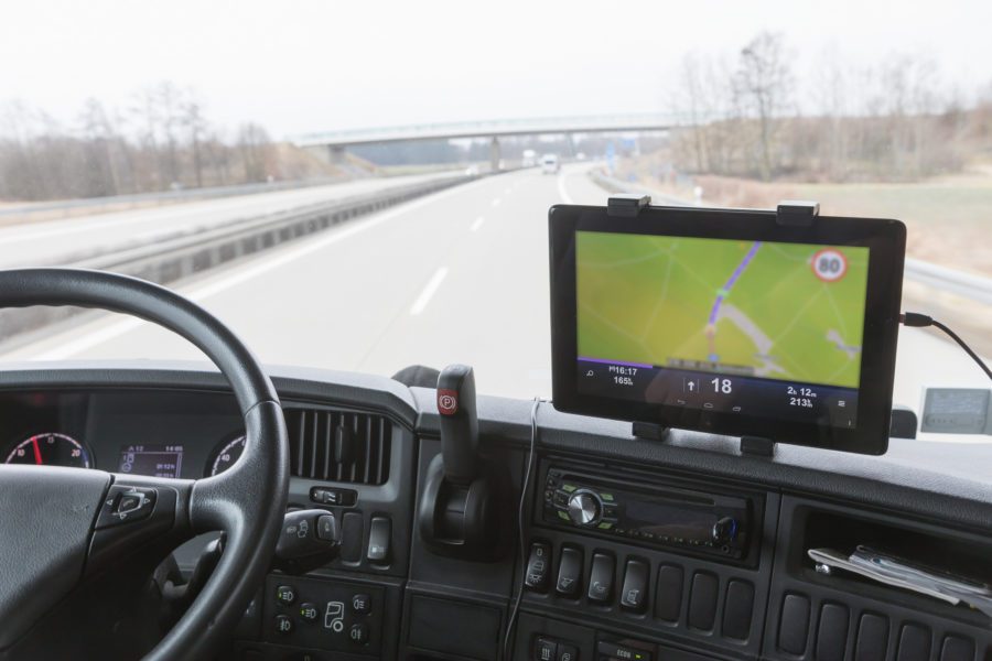 GPS mounted on car dashboard as it drives down empty highway