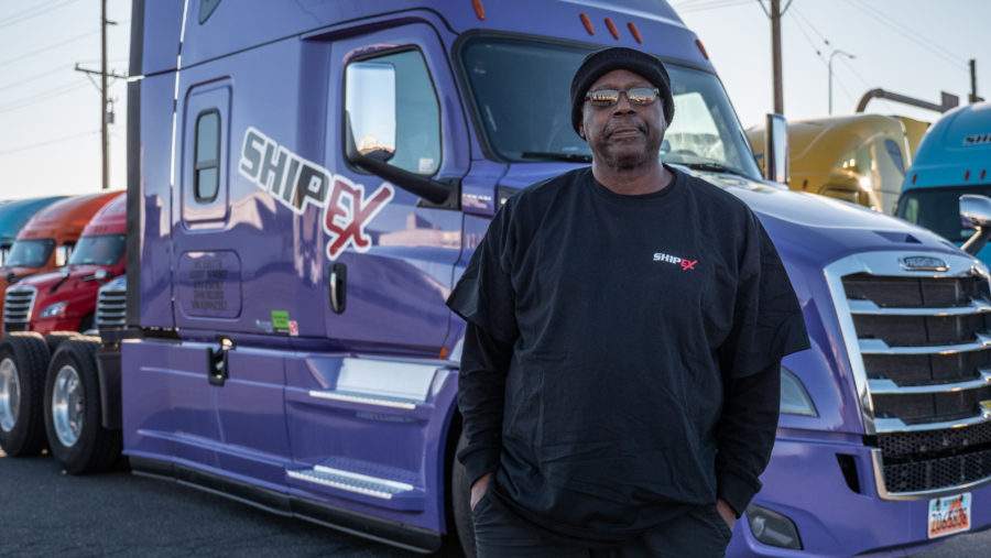 Truck driver standing in front of purple truck