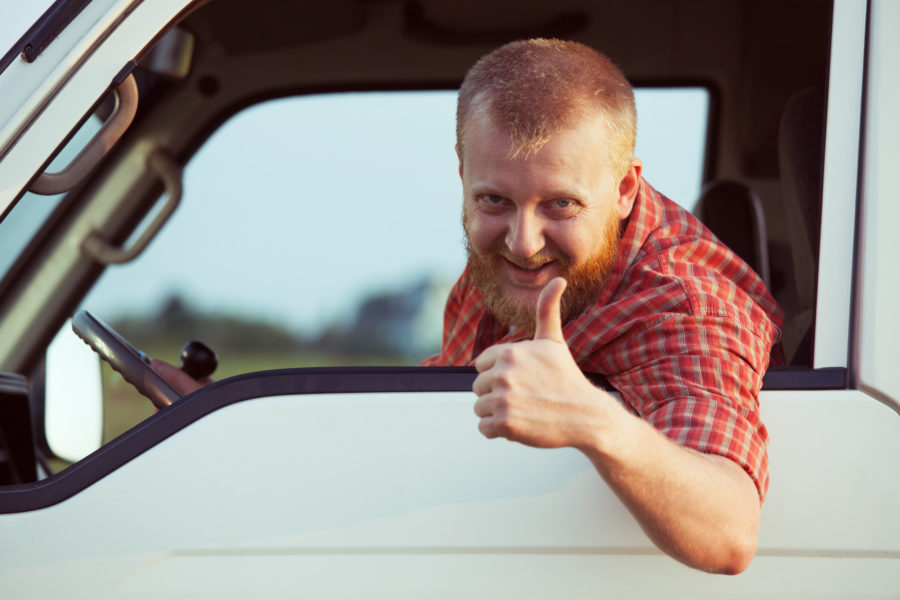 Truck driver making thumbs up outside of semi truck window