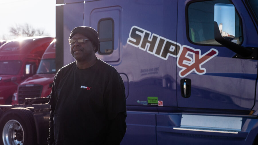 Truck driver standing in front of purple semi truck