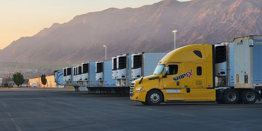 Yellow truck in front of row of refrigerated trailers