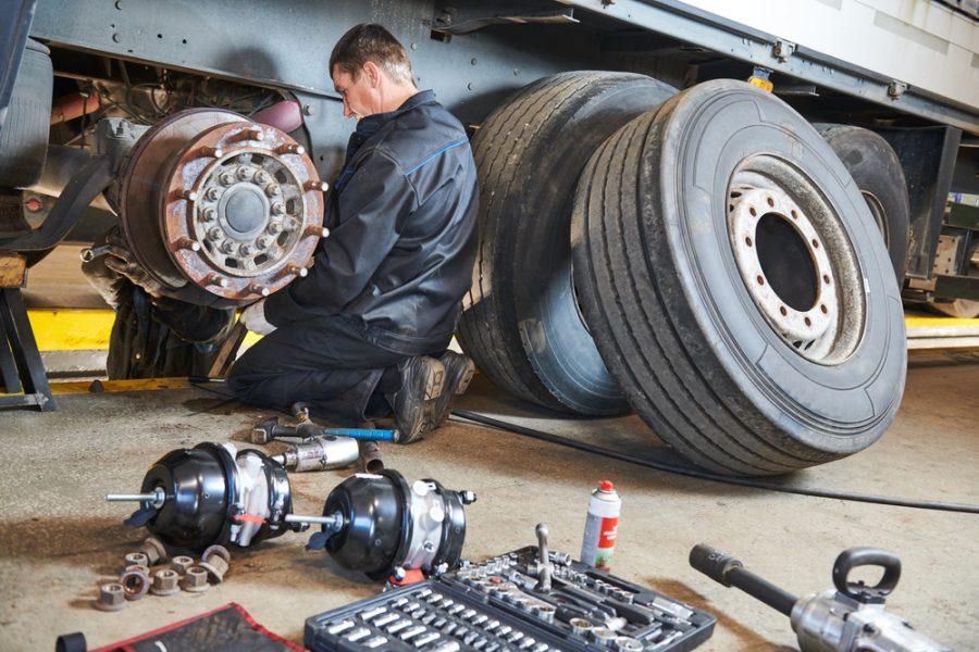 Truck repair service. Mechanic takes off tire for brake replacement