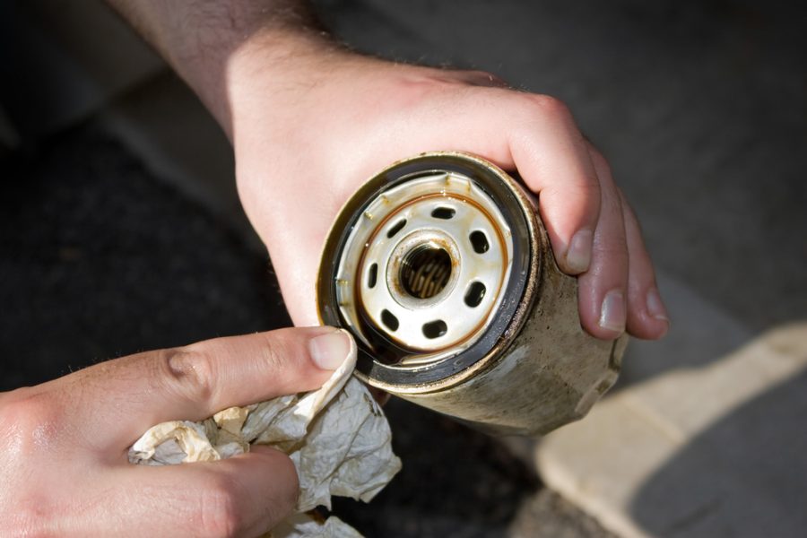 A backyard mechanic wipes the seal of a slightly used oil filter to reuse it for an additional 3000 miles. Others prefer to replace them each and every oil change.