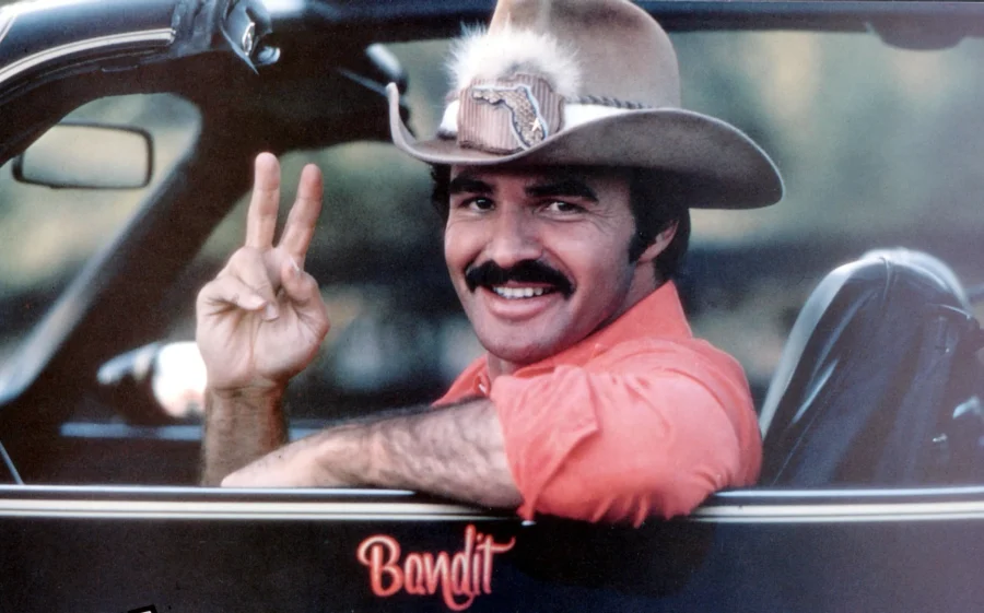 Smokey and the Bandit making a peace sign in a convertable