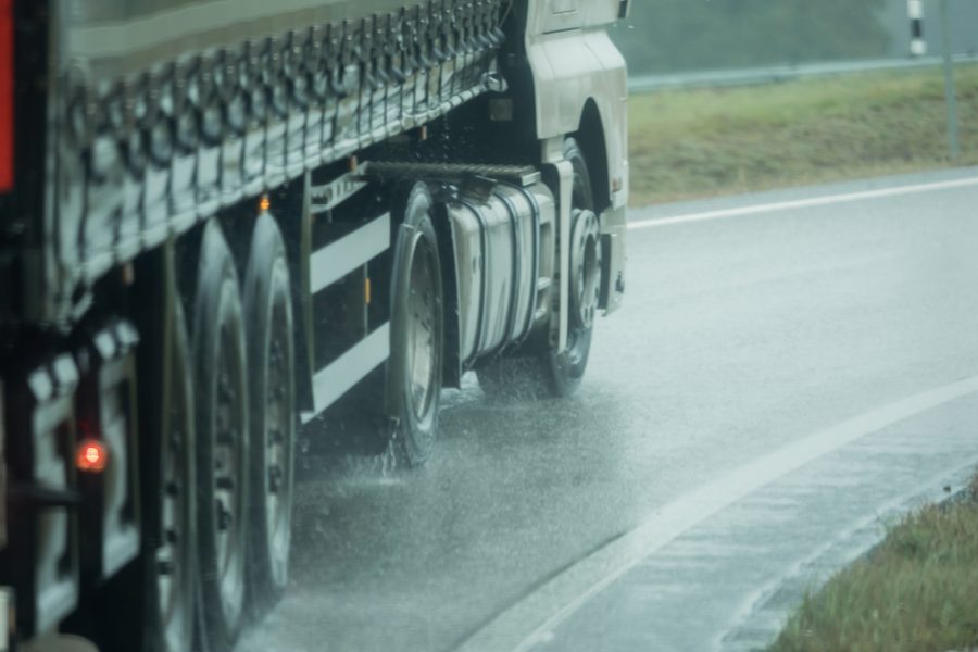 A truck is driving on the road in the rain