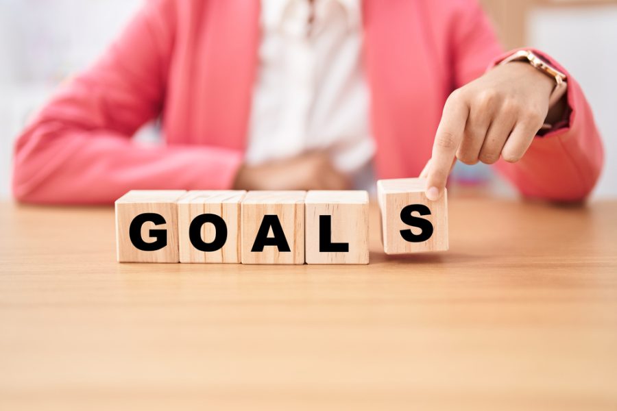 Business woman holding cubes with goals word on the table