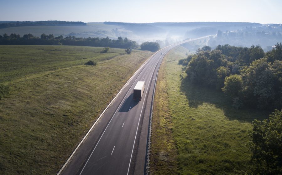 Aerial Top View of White Truck with CargoSemi Trailer Moving on Road in Direction.