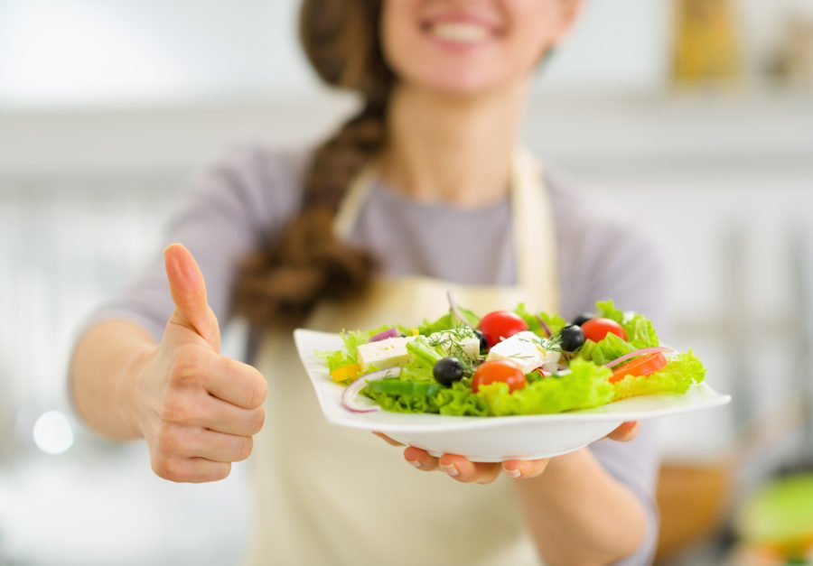 Woman holding a salad and making a thumbs up