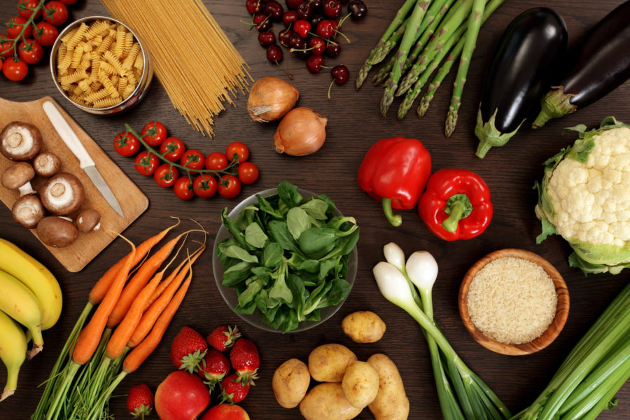 fruits, vegetables, and uncooked pasta spread on table.