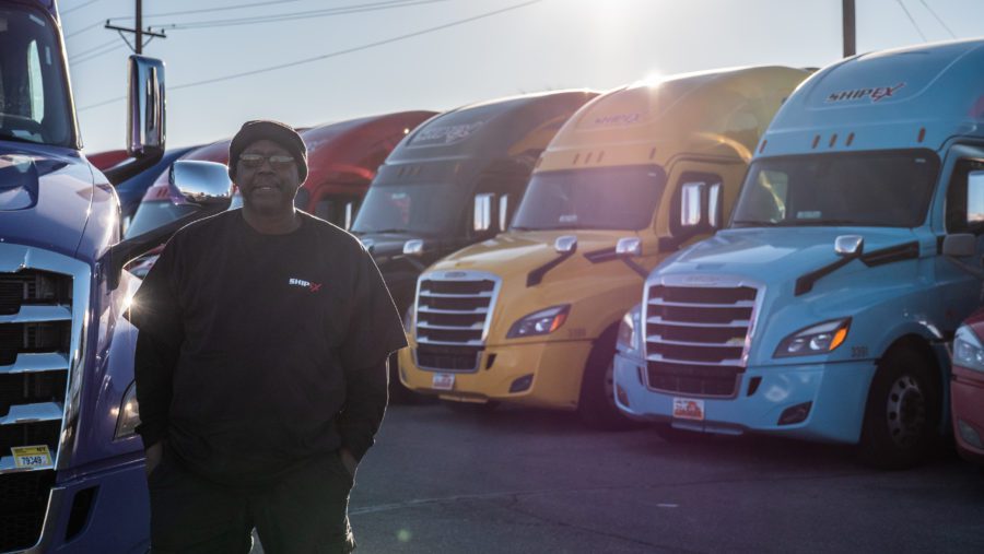 Truck driver standing in front of row of colorful trucks