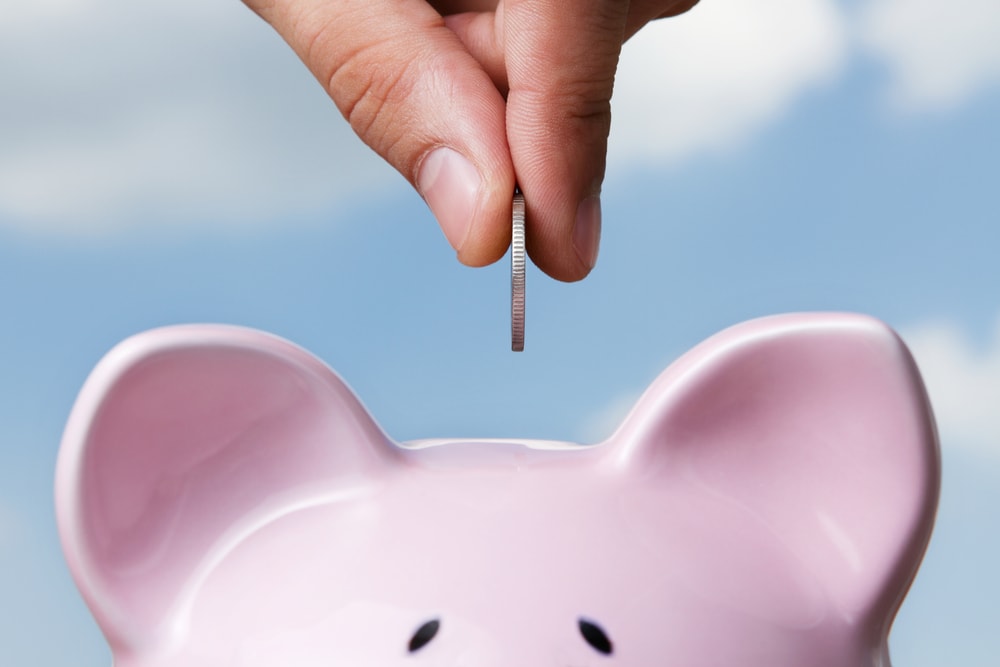 Man putting coin in piggy bank