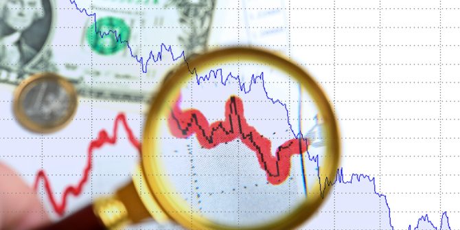 magnifying glass over chart going down with american dollar bill