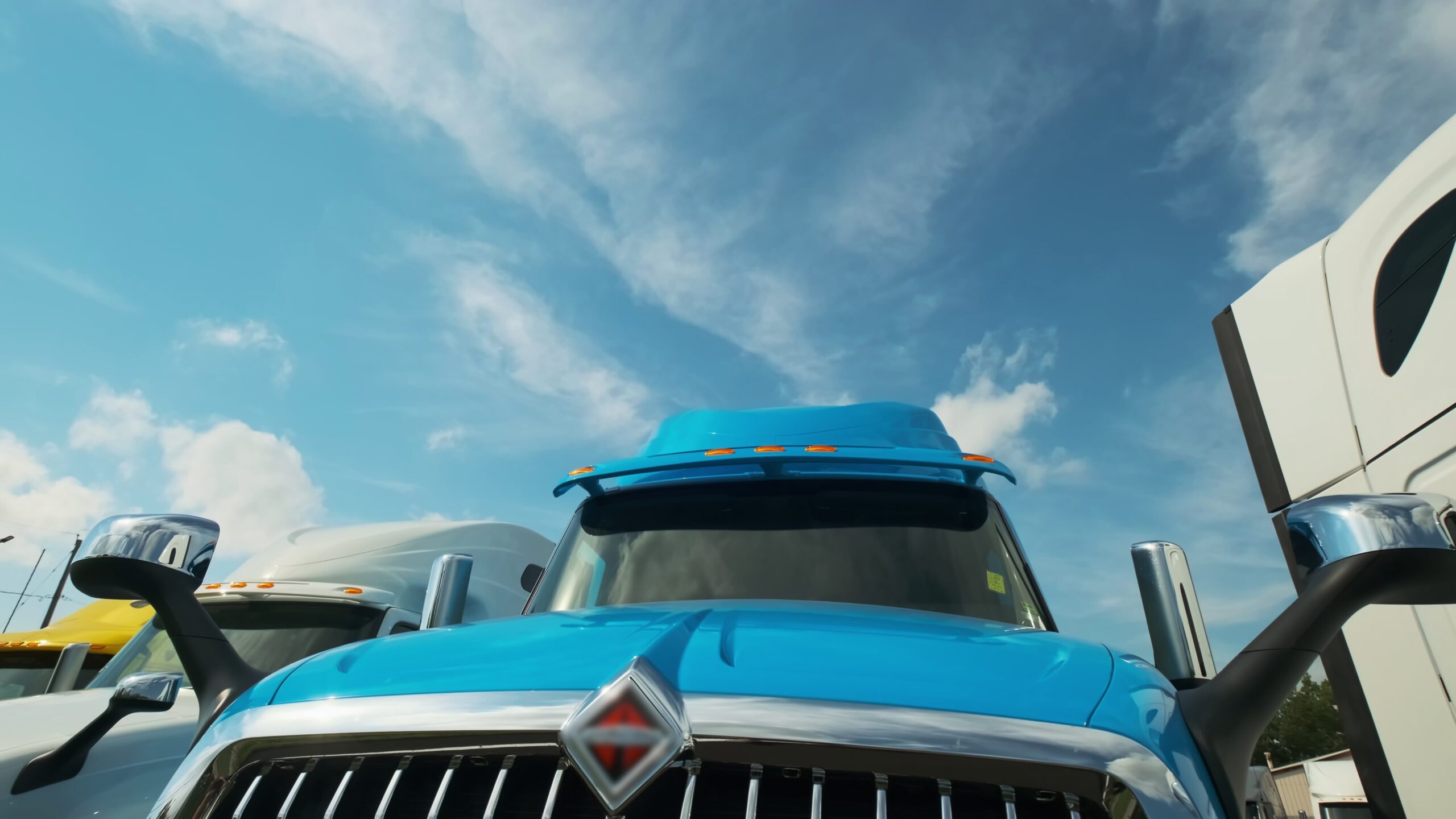 blue semi truck with blue skies and clouds in the background