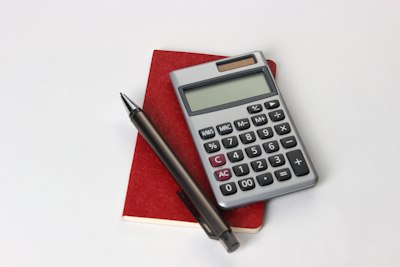 calculator and pen on a red notebook